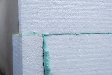 Installation of styrofoam insulation sheets on house facade wall for thermal protection.