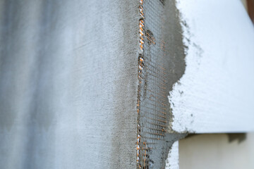 Installation of styrofoam insulation sheets on house facade wall for thermal protection.