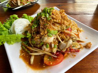 Thai spicy papaya salad Som Tam with shells