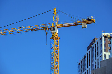 A crane near a house under construction against the blue sky
