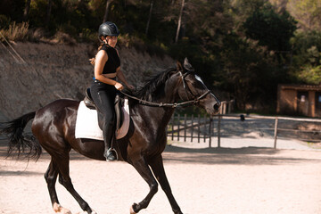 Young woman riding with her horse in evening sunset light, black horse, stalion