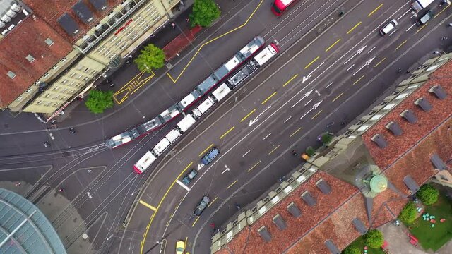 Top down aerial drone footage of the Bern city center with many tramway by the main train station in Switzerland capital city. The city has a very efficient public transportation system