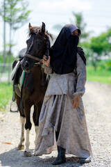 Portrait of Muslim woman with horse in the meadow