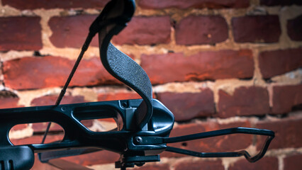 Part of modern compound crossbow handgun on the red brick wall background. Old weapon concept.