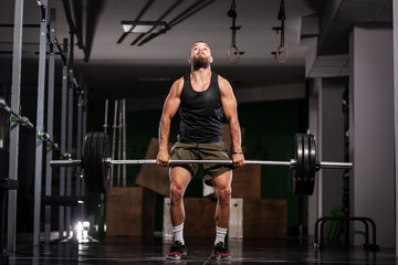 Muscular athlete lifting very heavy barbell
