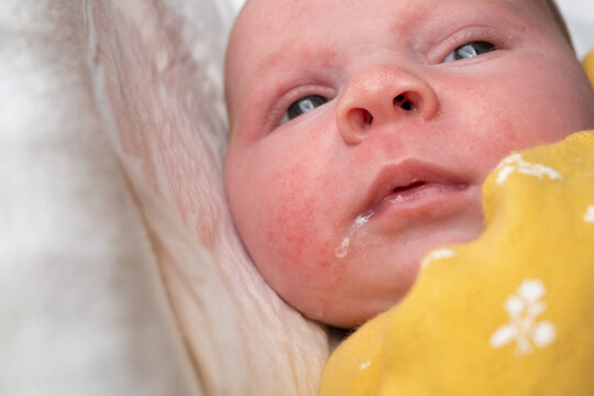 Newborn baby girl drooling close-up on white background