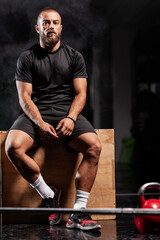 Fototapeta na wymiar Muscular athlete posing with weightlifting equipment. Smoke background