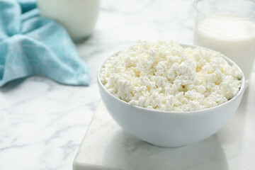 Delicious fresh cottage cheese in bowl on white marble table