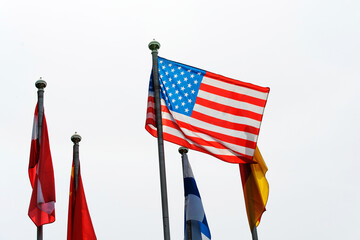 The American flag flutters from the flagpole, while other country symbols hang dejectedly. Foreground