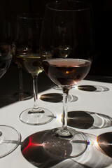 glasses with red white and rose wine on white table with dark shadows vertical view