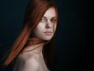 red-haired woman naked shoulders clear skin dark background