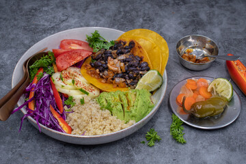 Vegan Mexican Bowl consisting of quinoa, beans, soft tacos, salad, pickles