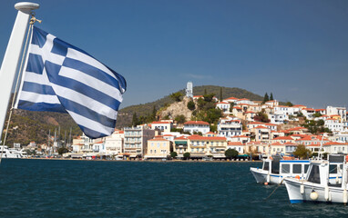 Griechische Flagge, im Hintergrund die Insel Poros.