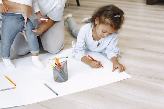 African-american girl lying on floor and drawing with mother.