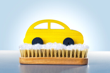 Cleaning the toy yellow car on a blue background. Car wash concept.