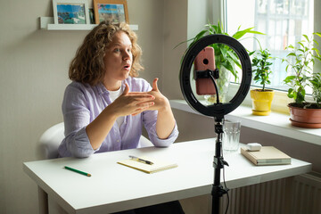 curly woman talking with smartphone standing with led light for instagram blog blogger social