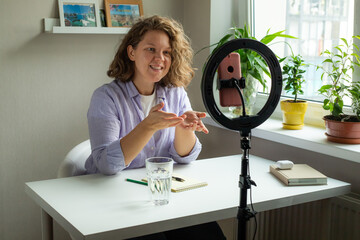 curly woman talking with smartphone standing with led light for instagram blog blogger social