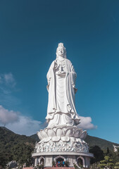 Fototapeta na wymiar Large white Buddhist statue of lotus flower in the mountains. Big buddha with blue sky on the background