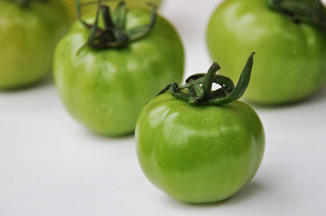 Green tomatoes on a white background. Some whole fresh green tomatoes, close up