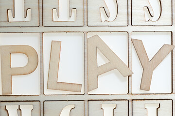 the word "play" in wooden letters on a stencil and white background