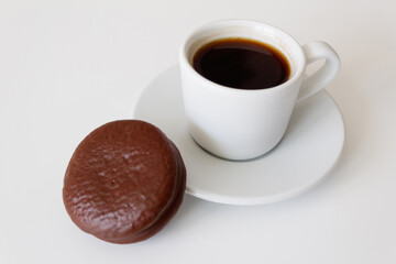 Delicious, hot coffee in a white mug on a saucer with chocolate tender cookies. Daily breakfast for one person. Top side view