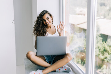 Young woman have video call on laptop from home office Workplace on the windowsill. Concept of...
