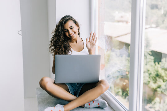 Young woman have video call on laptop from home office Workplace on the windowsill. Concept of female business, career, online shopping.