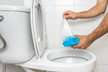 Hand throwing wet wipe into toilet - obrazy, fototapety, plakaty