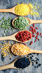 Top view of colorful dry organic cereal and grain seed pile in wooden spoon consisted of mung bean, pumpkin seed, goji berry, corn, and black bean on grunge background