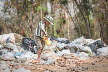 A poor boy collects trash from a landfill in the suburbs. Life and way of life of the poor Concept of child labor, poverty, environment. Waste separation.