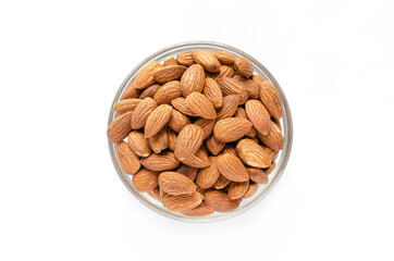Top view of dry organic almond seed pile in glass bottle on white background