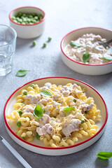 Pasta with ham, green peas and creamy sauce, selective focus