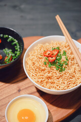 Instant noodles in a bowl with chili pepper on old wooden table
