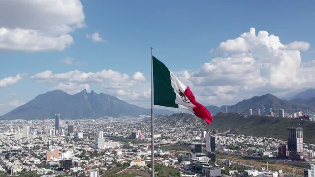 Bandera de M&eacute;xico flameando en el cielo de Monterrey con el Cerro de la Silla al fondo