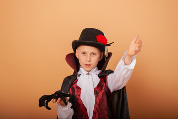 American-looking boy with a spider in his hands dressed as Count Dracula vampire