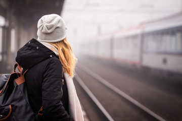Travel by train. Woman waiting for train on foggy railway station