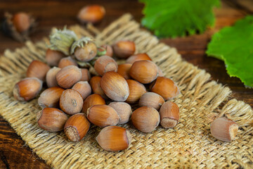 Hazelnuts on a wooden background with green leaves. Contains beneficial vitamins and minerals.