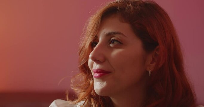 Giovane ragazza modella italiana con giacca rossa e camicia bianca &egrave; seduta sul divano rosso di casa