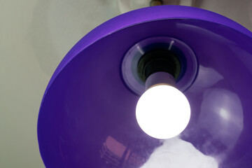 Lighting light bulb in purple plastic pendant.