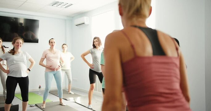 Yoga class of pregnant women practicing fitness enjoying healthy lifestyle. Group workout in yoga fitness studio