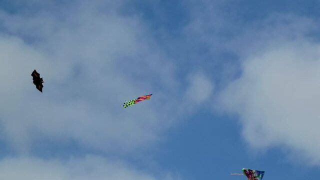3 kytes 3 kites flying against a cloudy sky. One of them is a halloween kite