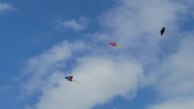 3 kytes 3 kites flying against a cloudy sky. One of them is a halloween kite