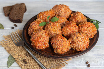Meat balls on a light background with sage and parsley leaves. Homemade lunch.