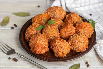 Meat balls on a light background with sage and parsley leaves. Homemade lunch.