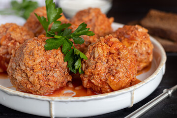 Meat balls on a wooden background with sage and parsley leaves. Homemade lunch.