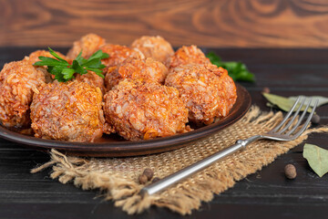 Meat balls on a wooden background with sage and parsley leaves. Homemade lunch.