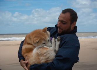 young beard man hugging dog at beach. shiba inu. friendship love dog concept