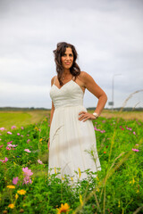 Fototapeta na wymiar Junge hübsche Frau im Brautkleid in einer Blumenwiese