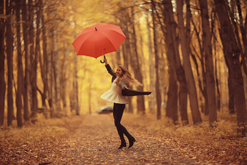 young woman dancing in an autumn park with an umbrella, spinning and holding an umbrella, autumn walk in a yellow October park