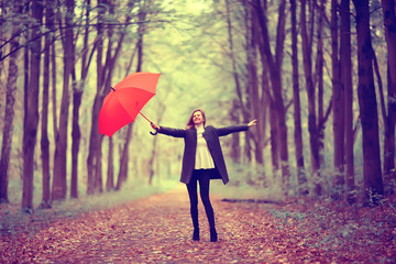 young woman dancing in an autumn park with an umbrella, spinning and holding an umbrella, autumn walk in a yellow October park